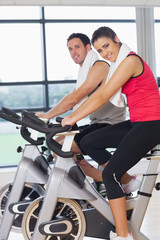 Fototapeta na wymiar Young woman and man working out at spinning class
