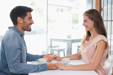 Obraz na płótnie Canvas Romantic couple holding hands at coffee shop