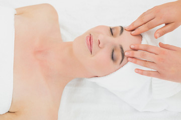 Hands massaging a beautiful womans forehead at beauty spa