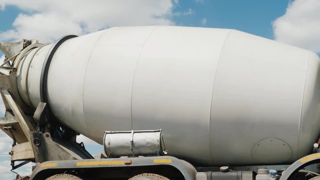 A large industrial concrete mixer, a tank with an ieton rotates against the sky. Concrete delivery and building materials concept