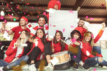 young group of fans dressed in red color watching a sports event