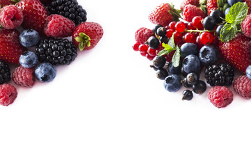 Mix berries and fruits at border of image with copy space for text. Black-blue and red food. Ripe blackberries, blueberries, strawberries, currants and raspberries on white background. 