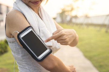 Female runner jogging and using smartphone to listening music in the park, Outdoor workout