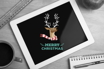 Merry Christmas message against overhead of tablet on desk