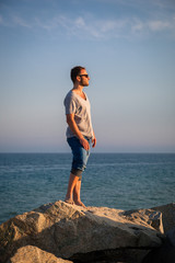 YOUNG MAN STANDING ON ROCKS