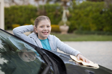 Teenage girl washing a car on a sunny day