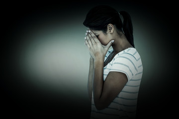 Side view of upset woman covering face against grey vignette