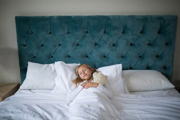 Obraz na płótnie Canvas Girl sleeping on bed with teddy bear in bedroom