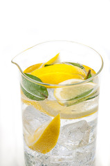 A full jug of drink from ice, lobules of juicy yellow lemon and crystal clear water.