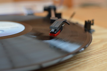 Closeup of tonearm and stylus on a wooden vinyl record player