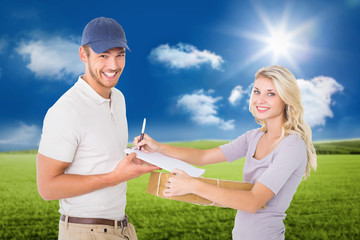 Happy delivery man giving package to customer against sunny green landscape