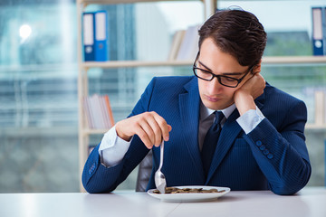 Funny businessman eating gold coins in office