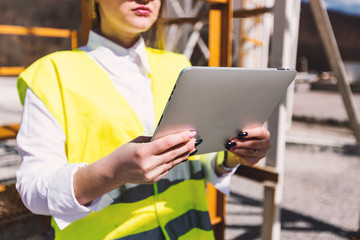 Close up view of female worker in high visibility vest holding tablet