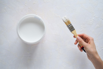 Repair in the house. Paint brush and paint on the background of white walls.