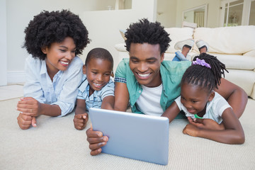 Happy family lying on the floor using tablet