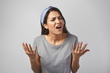Beautiful dark haired young European woman frowning and gesturing emotionally, holding hands in...