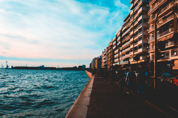 Fototapeta premium promenade of thessaloniki with darken tourist sillhouetts and port in the background
