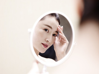 young asian woman looking at self in mirror