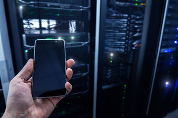 A hand with a smartphone on a data center background