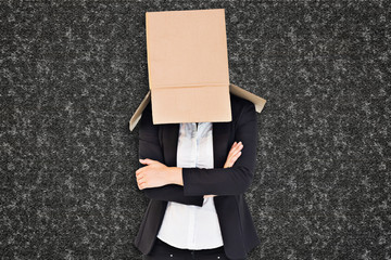 Businesswoman lifting box off head against black background