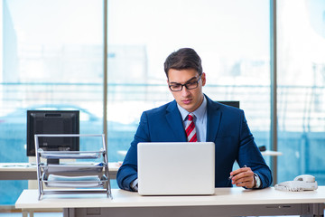 Young handsome businessman employee working in office at desk