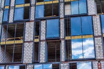 Glazing of the built building, the sky is reflected in the Windows of the house under construction