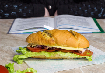 Sandwich in the foreground, in the background a girl doing homework