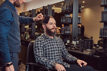 Professional hairdresser uses a brush, almost finished hairstyle. 