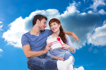 Couple sitting on floor together against cloudy sky