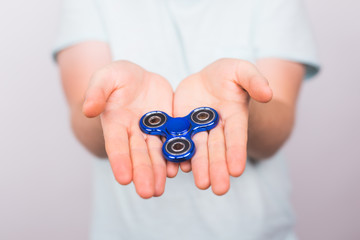 male hand holding popular fidget spinner toy on white background, anxiety relief toy, anti stress and relaxation fidgets