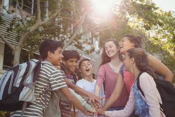 Happy school kids forming hand stack in campus