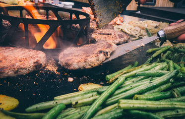 Grillgemüse und Burger mit Bacon auf der Feuerplatte grillen