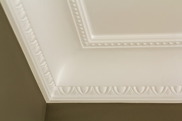 Ornamental white molding decor on ceiling of white room close-up detail. Interior renovation and...