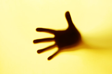 Orange hand silhouette behind a glass