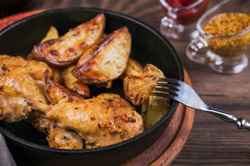 Fried chicken legs with fried potatoes in pan