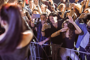 Fototapeta na wymiar Cheerful young crowd photographing performer at nightclub