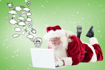 Santa lies in front of his laptop against green vignette