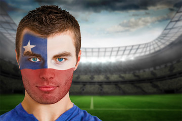Composite image of chile football fan in face paint against large football stadium with lights