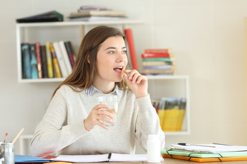 Student taking a pill to relief illness symptoms at home