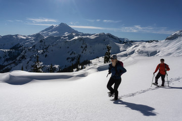 Adventurous man and woman are snowshoeing in the snow. Taken in Artist Point, Northeast of Seattle, Washington, United States of America.