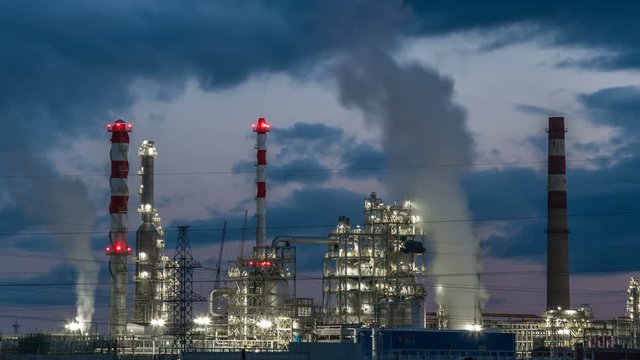 Close-up of industrial pipelines of an oil-refinery plant at twilight. Timelapse 4K