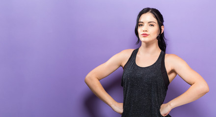 Powerful young fit woman posing on a solid purple background
