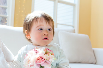 Fototapeta premium Happy toddler boy playing with flowers in his house