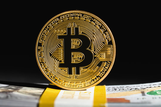 Bitcoin cryptocurrency coin with USD cash on a dark background