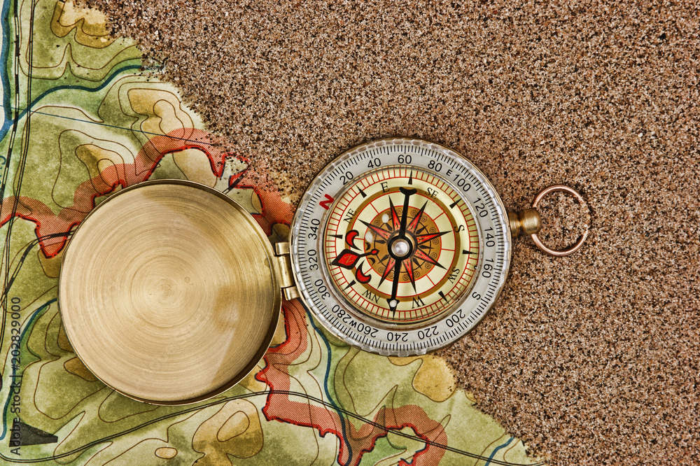 Wall mural compass on the map with sand