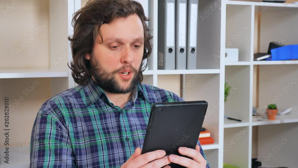 Poster portrait hipster man with beard using digital tablet for video chatting. guy has online conversation
