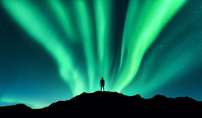Aurora borealis and silhouette of standing man. Lofoten islands, Norway. Aurora and happy man. Sky...