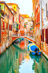 Canal with small bridge and motorboats in Venice