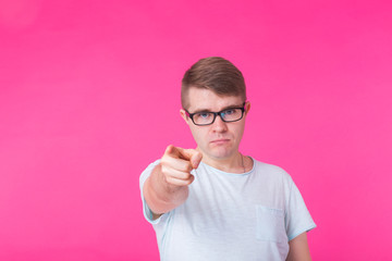 Young handsome man showing finger pointing towards the camera on pink background