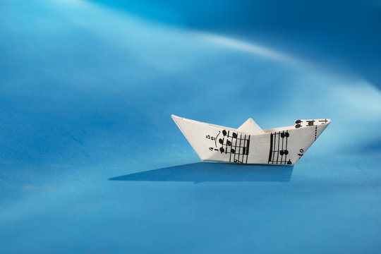 Paper boat made of musical score sheet in blue background